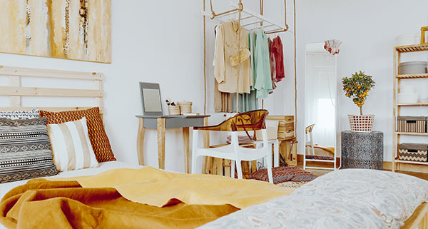 modern bedroom with a bed adorned in mustard blankets desk and mirror wall decorated with clothing rack and vibrant plant ideal for relaxation and creativity 4 home decor ideas 4 stylish furnishings