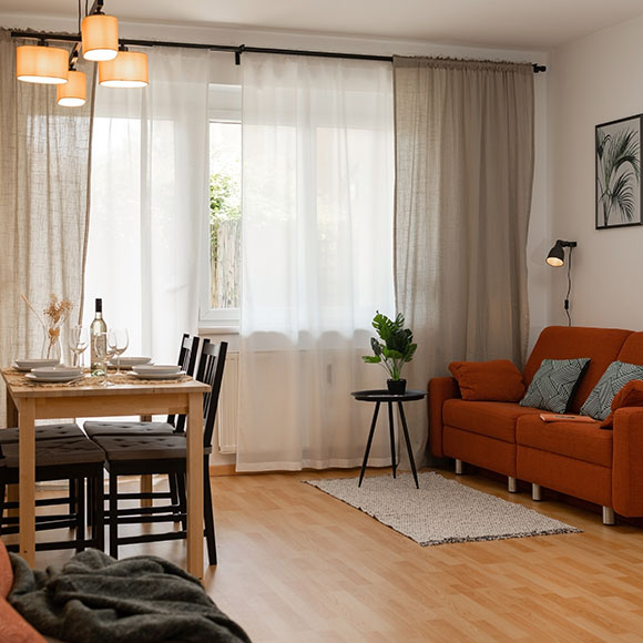 cozy living room with a dining area featuring an orange sofa wooden table dining utensils and houseplants natural light bright atmosphere 3 comfortable spaces