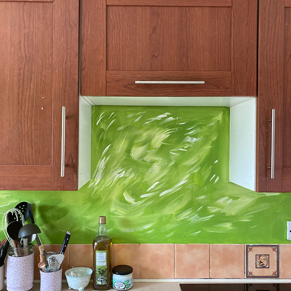 kitchen with green painted wall and wooden cabinets including cooking utensils and olive oil bottle